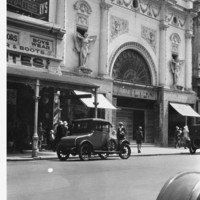 Image: Pedestrians and parked cars in front of ornate cinema facade