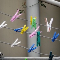 Image: Several colourful plastic clothing pegs are attached to a metal frame containing a number of separate clotheslines