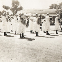 Group of women in white dresses and hats holding instruments. 
