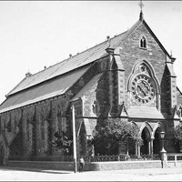 Image: A boy poses in front of the Baptist Church on the corner of Flinders Street and Divett Place. This church was built in 1861 to plans by Robert Thomas who also designed the Pilgrim Church. It features a rose window and front entrance with three arch