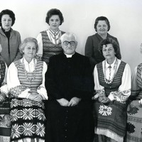 Seated priest with six women in Lithuanian national costume