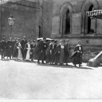 Image: A group of men and women in academic dress walk towards the entrance of Elder Hall on the way to their graduation ceremony