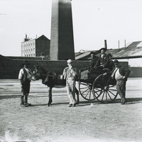 A group of men with cart standing outside the masonry perimeter wall of the copper smelter