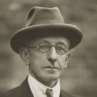 Image: black and white photo of man in glasses, hat and suit