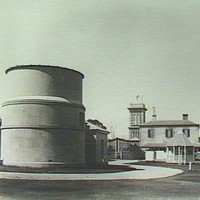 Image: large funnel like building with two story building in background