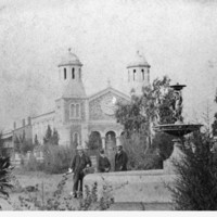 Image: three people standing next to fountain with church in background