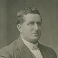 Image: Photographic portrait of a man in a suit jacket, vest and shirt. 