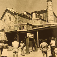 Sepia photo of group of people in front of an old stone mill building