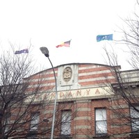 Image: top storey of red brick three-storey building, with three flags flying