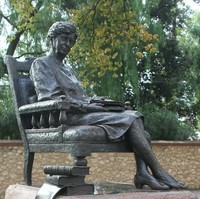 Image: bronze statue of seated woman with books