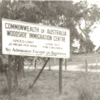 Image: sign amongst gum trees with buildings in background