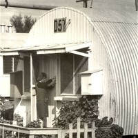 Image: woman at door of curved tin building