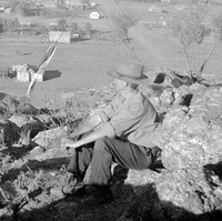 Image: man sitting on rocky outcrop overlooking township