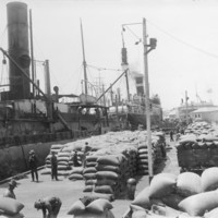 Image: large number of hessian bags being loaded or unloaded from steam ships
