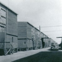 Image: row of tin buildings with car parked on dirt road
