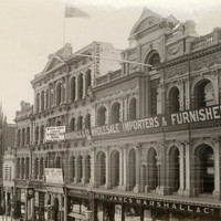Image: a grand four storey department store with a highly decorative facade. The ground floor has plate glass windows with displays with the remainder of the floors having a large number of arched windows. 