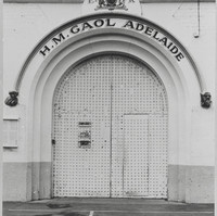 Image: a large metal arched door with a sign reading: "H.M. Gaol Adelaide"