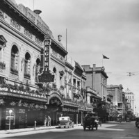 Image: a very ornate theatre building with plants hanging from and on top of its verandah as well as in window boxes on the second storey.