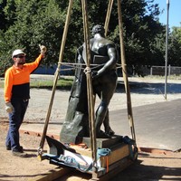 Image: man in hard hat and hi-vis supervising statue being lifted using hoist