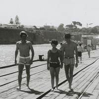 Image: People walking and others fishing with hand rods from a wooden jetty