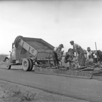 Image: Black and white photo of a drag box being used to spread hotmix (bituminous concrete), this method was a cheap way to provide a smooth surface, 10 November 1937.