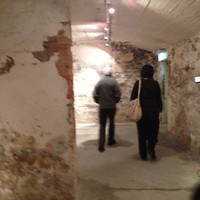 Image: two people walking through underground brick-walled rooms