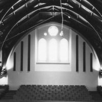 Image: The interior of a large hall with a hammerbeam roof and tiered seating on two levels.