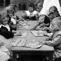 Image: several caucasian children sit around a wooden table playing with plasticine