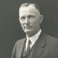 Image: Upper body portrait photograph of a man wearing a suit