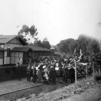 Image: group of people with flags gathered in front of building on railway tracks