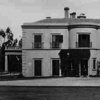 Image: Black and white photograph showing front of large, white two-storey building