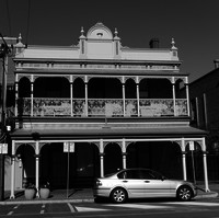 Image: two story brick building with painted ironwork and veranda