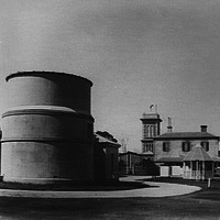 Image: large funnel like building with two story building in background