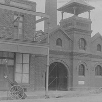 Image: sepia photo of large brick building with arched entrance