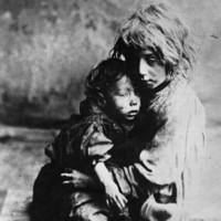 Image: two children in rags holding each other
