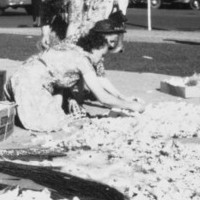 Women arranging flowers on the ground with buildings in the background