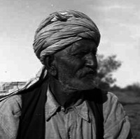 Image: An elderly man with a beard and turban stands in the central Australian desert