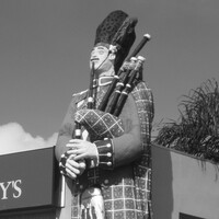 Image: large painted figure of a man in a kilt playing the bagpipes