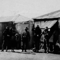 Image: Group of men standing in front of corrugated iron building 