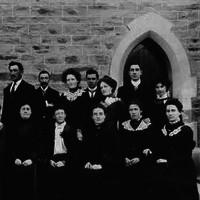 Image: men and women in dark coloured clothing pose in two rows for a formal photograph. 
