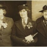 Three women standing together, all wearing hats and coats.