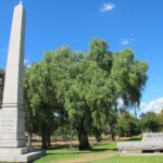 Image: a stone pillar and trough commemorating the Australian Light Horse and warhorses (1914-1918) are situated in a public park with a variety of trees and expanses of grass