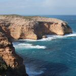 Image: A large bare cliff face juts out into the ocean