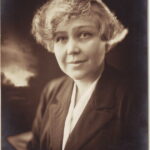 Image: A photographic head-and-shoulders portrait of an incredibly attractive young woman with light-coloured eyes and an ear-length 1920s haircut