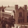 Image: a high angle photograph of a large stone hall with towers and three doors under a large window at the front.