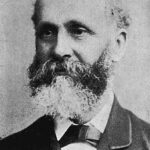 Image: A balding, middle-aged man with a bushy full beard poses for a photograph. The man is wearing late Victorian-era attire