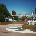 Image: A large plinth painted with an alternating black and white pattern, and emblazoned with the words ‘Keep Left’ and directional arrows at its base, is displayed in a park area made of brick