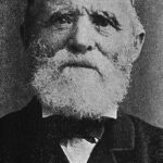 Image: A photographic head-and-shoulders portrait of an elderly Caucasian man with a white beard. He is wearing a late nineteenth century suit with bowtie