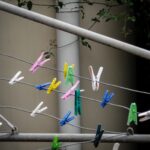 Image: Several colourful plastic clothing pegs are attached to a metal frame containing a number of separate clotheslines