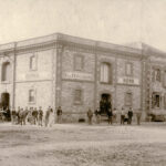 Image: group of men standing in front of large stone building